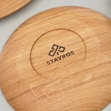 Круглая деревянная тарелка с виноградом и грецкими орехами, на заднем плане лежат круассаны и пшеничные колоски