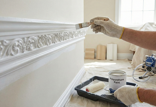 Покраска лепнины из полиуретана: кистью прокрашивают орнаментальный карниз, аккуратно проходя по рельефу без подтеков