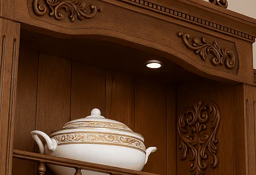 Классический деревянный шкаф с изысканной резьбой и декоративными элементами, украшенный посудой в золотой отделке.