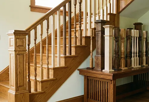 Балясины для лестницы из дерева разных форм и размеров рядом с деревянной лестницей в интерьере дома