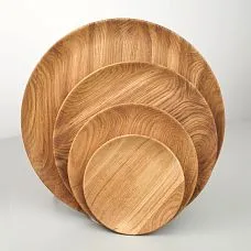 Несколько деревянных тарелок разных размеров, сфотографированных в профиль.