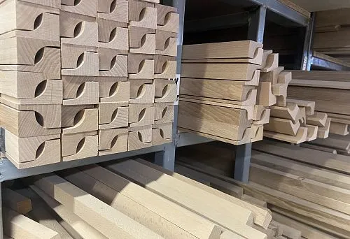 Тонкие деревянные палки и фигурные заготовки с декоративной выборкой, аккуратно сложенные на полках склада