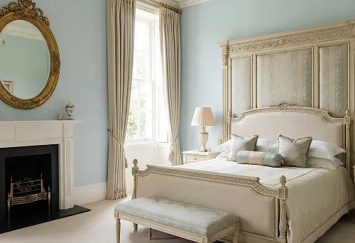 Неоклассическая спальня в голубых тонах: высокий белый плинтус и классический каминный портал; над камином овальное зеркало в золочёной резной раме
