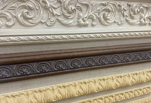 Набор резных деревянных багетов разных цветов и фактур, представленных на стенде