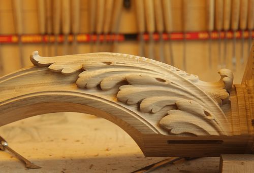 Hand carving of oak during furniture production, decorative element with elegant floral ornament on wooden blank