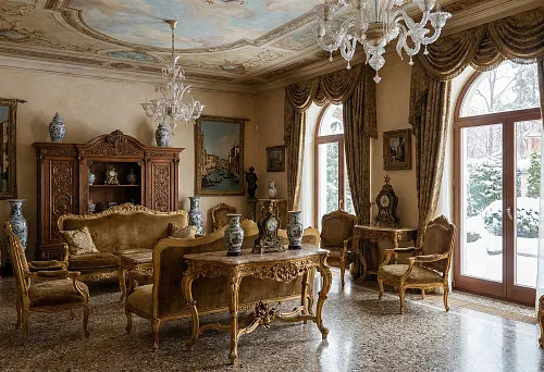Italian Baroque furniture in the living room: gilded armchairs and a sofa, carved table, crystal chandeliers and heavy curtains at arched windows