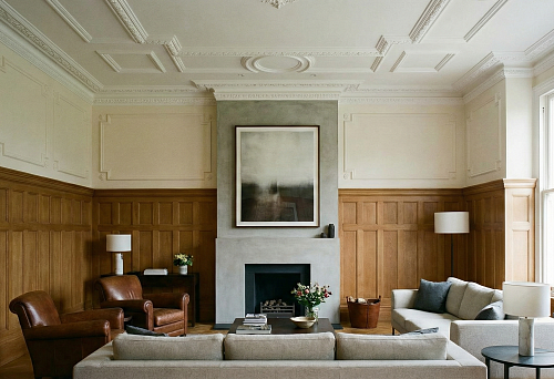 Wall finishing in a private house with wooden panels and polyurethane moldings in a living room with a fireplace
