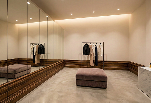 A full-height mirror wall and a high wooden baseboard create an interior in the style of an expensive boutique with soft lighting