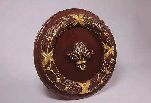 Round wooden relief with carved laurel wreath and central element in the form of a golden lily, executed in the technique of artistic stucco.