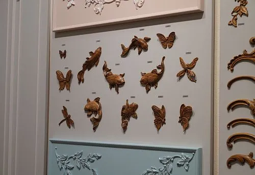 Collection of carved wooden figurines in the shape of fish and butterflies, neatly arranged on a stand with different colored panels.