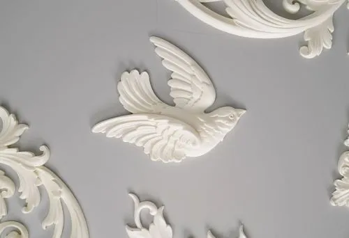 Polyurethane decorative element in the shape of a flying bird on a gray wall