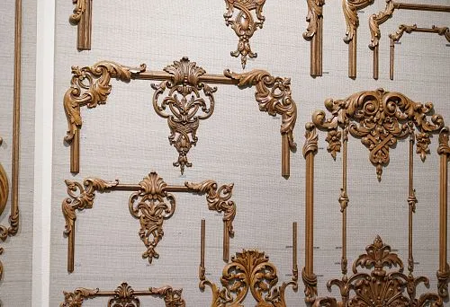 Carved wooden panels and frames of various shapes and sizes, arranged on a demonstration surface