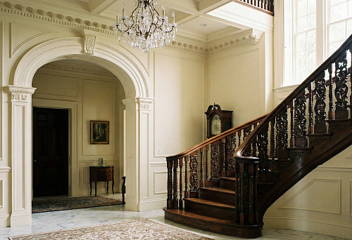 Polyurethane stucco molding and a decorative arch in the grand hall with a wooden staircase and carved balusters