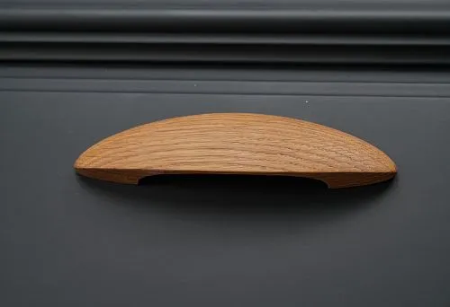 Furniture handle with ergonomic design in natural wood color.