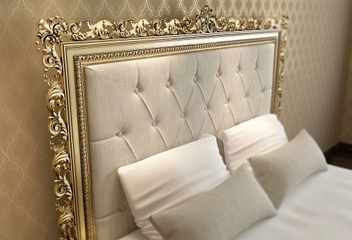 Close-up of a decorative bed headboard with carving and gold elements