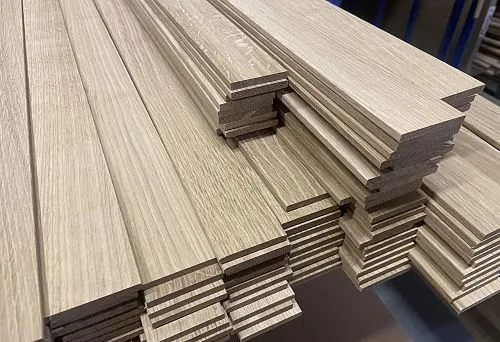 Wooden sticks with smooth surface and profiled shape, neatly stacked on a production table