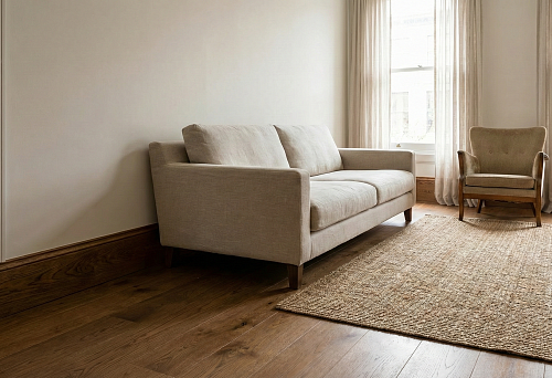 Wooden floor skirting board along the wall in a bright living room: the bottom line connects the floor and furniture with a soft sofa