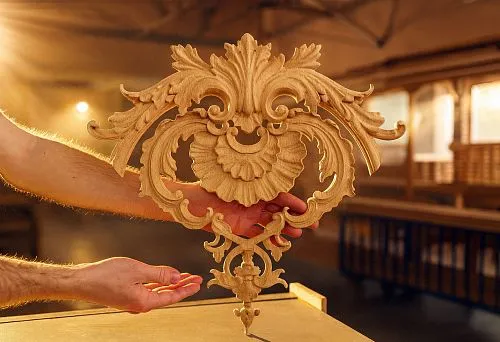 Carved Wooden Decorative Element in the Hands of a Craftsman at Production in Warm Rays of Light