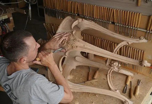 The master hand-carves an exquisite pattern on an unpainted wooden table