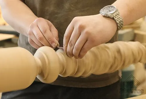 The craftsman polishes a precisely turned wooden detail on a lathe during woodturning processing