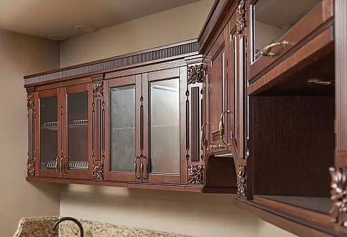 Classic kitchen set made of dark solid wood with decorative carving and glass fronts