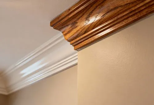 Combination of wooden and white polyurethane cornice at the junction of wall and ceiling.