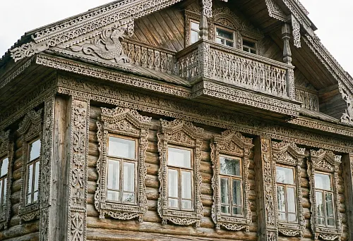 House adorned with wood carvings: lace-like window frames, carved cornice, and traditional facade of wooden architecture