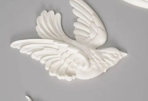 Process of creating ceiling molding: decorative white bird with spread wings and elegant branch