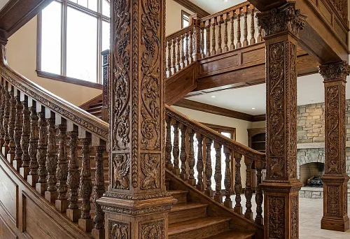 Wooden balusters and support pillars: a carved staircase with massive columns and richly decorated railings in a classic interior.