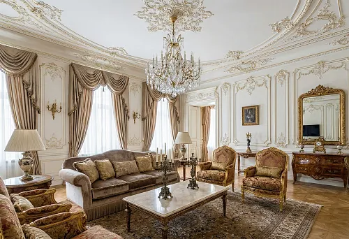 Palace interior in an apartment: decorative stucco on walls and ceiling, crystal chandelier, and classic furniture with gilding