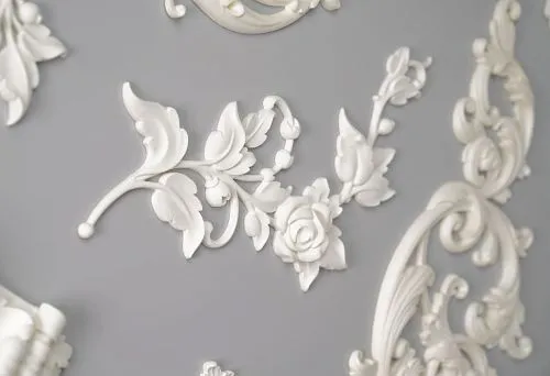 Fragment of polyurethane relief decor with floral ornament on gray background