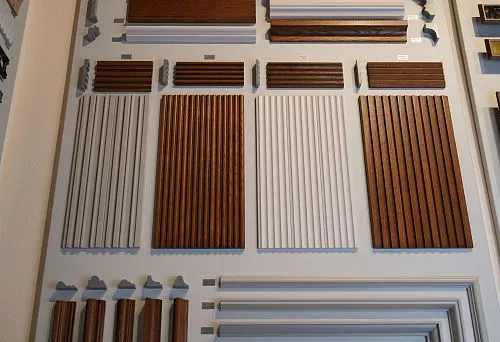 Collection of wall decorative panels and moldings in various shades and profiles, displayed on the stand.
