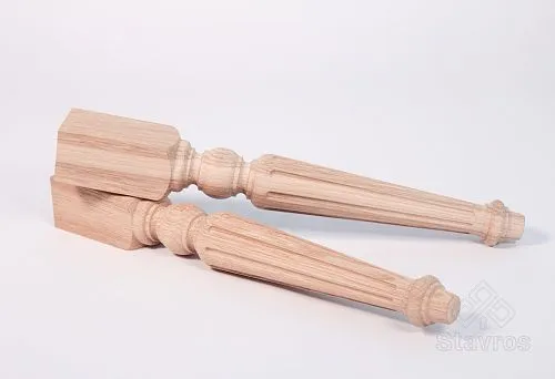 Two long carved wooden legs made of light wood, lying on a white surface.