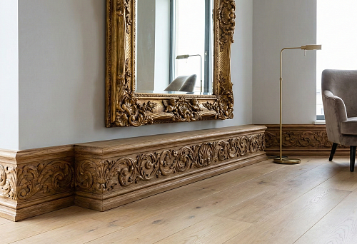 Modern apartment with palace aesthetics: wide carved wooden baseboard with ornament along the wall