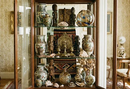 Types of Decorative Elements: Glass Display Case with Collectible Vases, Figurines, and Ethnic Textiles in a Classic Interior