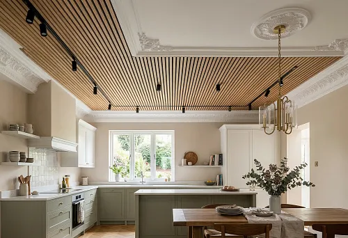 Ceiling made of slatted panels in the kitchen and stucco on the ceiling in a light interior with an island and a dining table
