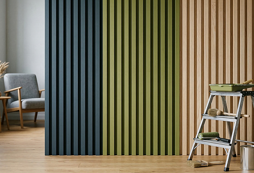 Slatted wall panels for painting in an interior with blue, olive, and wood tones, stepladder, roller, and brushes for wall finishing