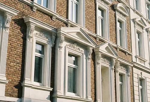 Facade windows with polyurethane decorative frames on a brick house
