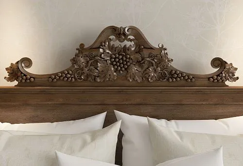 Carved wooden headboard with grapevine ornament &mdash; an accent in classic-style interiors