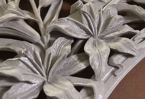 A fragment of decorative molding with three-dimensional flowers in silver finish, highlighting the elegance of a classic interior.