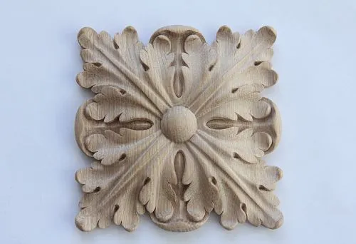Wooden carved decoration element with a classic leaf ornament on a light background,