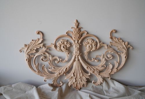 Large carved furniture applique made of natural wood with classic ornament, light background