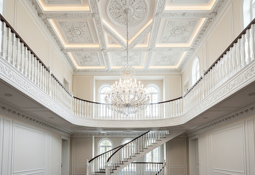 Double-height hall with decorative ceiling molding that connects two floors into a single architectural composition