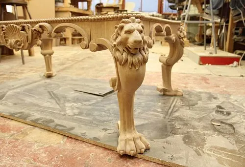 Carved base for countertop with handcrafted elements in the form of a lion's head and paw.