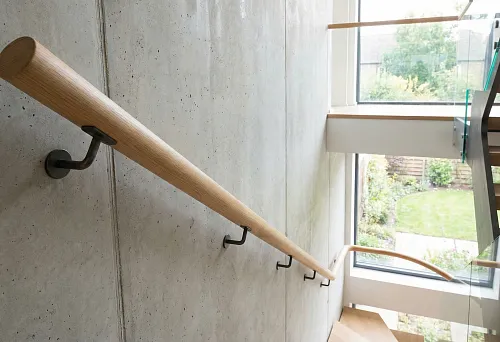 Round Wooden Railings on a Concrete Wall in a Modern Stairwell