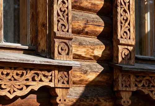 Carved wooden window trims in Russian style with patterned carving and expressive play of light and shadow on the house facade