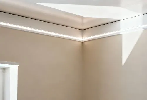 Skirting board for a stretch ceiling with integrated LED lighting, installed around the perimeter of the ceiling in a modern interior with soft lighting accents.