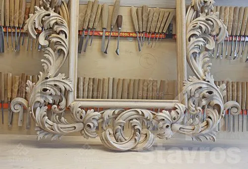 Interior wooden frame with patterns for a mirror against a background of woodworking tools