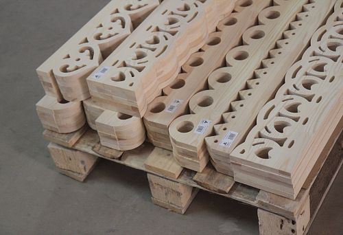 Stack of traditional carved casings made of light wood before processing.