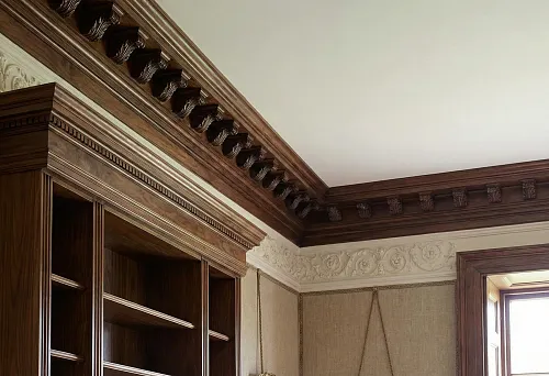 Wooden ceiling cornices in classic interior: massive top line with carved ornament along the room perimeter